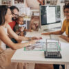 Four people, married couple with baby son in modern travel agency talking to a woman who is working there, they are planning a vacation.