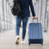 Unrecognizable Man With Bag And Suitcase Walking In Airport Terminal, Rear View Of Young Male On His Way To Flight Boarding Gate, Ready For Business Travel Or Vacation Journey, Cropped, Copy Space