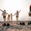 Family vacation holiday, Happy family running on the beach in the sunset. Back view of a happy family on a tropical beach and a car on the side.