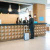 Businessman making booking at front desk with Latin receptionists in hotel lobby