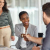 Happy black businesswoman and businessman shaking hands at meeting. Professional business executive leaders making handshake agreement. Happy business man closing deal at negotiations with african american woman.