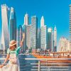 Cheerful asian traveler girl walking on a promenade in Dubai Marina district. Travel destinations and tourist lifestyle in UAE