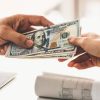 Businessman hand sending money to another business person. Transaction, payment, salary and banking concept.