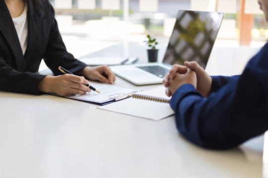 The manager is reading the resume and is interviewing the new employee. Negotiating business and signing a contract. Lawyer and legal advisor.