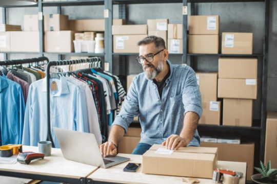 Mature men at online shop. He is owner of small online shop. Receiving orders and packing boxes for delivery.