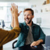 empower Successful business people giving each other a high five in a meeting. Two young business professionals celebrating teamwork in an office.