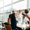 Shot of a group of businesspeople high fiving while sitting in a meeting Shot of a group of businesspeople high fiving while sitting in a meeting